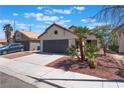 Single-story home with terracotta roof, rock landscaping, concrete driveway and desert palm tree at 4149 Compass Rose Way, Las Vegas, NV 89108