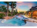 Backyard pool and jacuzzi with beautiful rock features and palm trees surrounding at 4200 Scott Peak Ct, Las Vegas, NV 89129