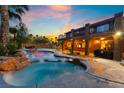 Backyard pool and jacuzzi with beautiful rock features and ample lounge space, as well as an upper level balcony at 4200 Scott Peak Ct, Las Vegas, NV 89129