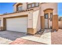 Close up of charming home featuring a tile roof, neutral stucco, and an attached two-car garage at 4514 Calico Cliff Ct, North Las Vegas, NV 89031