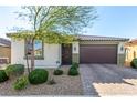 Charming single-story home showcasing a well-manicured lawn and a two-car garage, complete with stone accents and desert landscaping at 5633 Alitak Bay St, North Las Vegas, NV 89081