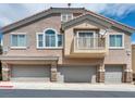 Three-story exterior with gray garage doors and stone accents at 8728 Tom Noon Ave # 103, Las Vegas, NV 89178