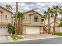 Inviting two-story home with a terra cotta roof, two-car garage and manicured landscaping with tall palm trees at 9966 Mystic Moss St, Las Vegas, NV 89183