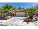 Inviting single-story home featuring a two-car garage, desert landscaping, and mature palm tree at 11073 Gateview Ln, Las Vegas, NV 89144