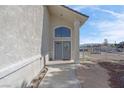 Front entrance of home features arched window above gray double doors and concrete walkway at 1581 Cavalry St, Pahrump, NV 89048