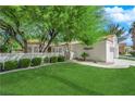 Landscaped front yard featuring a lush lawn, mature trees, and a decorative gate leading to the entrance at 240 Windsong Dr, Henderson, NV 89074