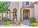 Inviting home entrance with arched porch and lush landscaping leading to the front door at 2862 Starling Summit St, Henderson, NV 89044