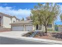 Tan two-story home with a three-car garage and drought-resistant landscaping at 3079 Evening Mist Ave, Henderson, NV 89052
