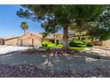 Single-story home featuring a two-car garage, palm tree, mature shade tree and manicured landscaping at 4004 Nancy Margarite Ln, Las Vegas, NV 89130