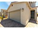 Attached two car garage with a brick paver driveway and landscaped features at 4517 Swimming Minnow Ave, Las Vegas, NV 89141