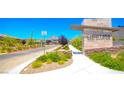 Attractive community entrance with desert landscaping, mountains in the distance, and decorative signage at 12101 Arrebol Ave, Las Vegas, NV 89138