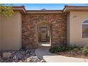Charming home entrance with a stone archway, rustic wood door, and well-kept landscaping at 1981 Trophy Elk Ave, Logandale, NV 89021