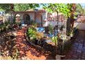 Landscaped front yard with winding pathways, decorative plants, water features, and mature trees providing shade and beauty at 4834 E Van Buren Ave, Las Vegas, NV 89110
