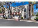 Charming townhome featuring a stucco facade, red tile accents, and mature landscaping at 611 Spyglass Ln, Las Vegas, NV 89107