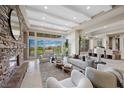 Bright living room featuring a stone fireplace, contemporary furnishings and golf course views at 1472 Macdonald Ranch Dr, Henderson, NV 89012