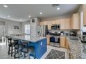 Open kitchen featuring stainless steel appliances, granite countertops, and a blue island with barstool seating at 2928 Sunday Silence Rd, North Las Vegas, NV 89086