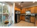 Well-lit kitchen featuring stainless steel appliances, wooden cabinetry and breakfast table overlooking the backyard at 6623 Brick House Ave, Las Vegas, NV 89122