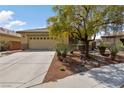 Charming single-story home with desert landscaping and mature shade tree, complemented by a well-maintained lawn and driveway at 4217 Box Canyon Falls Ave, North Las Vegas, NV 89085