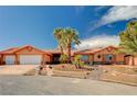 Desert home featuring a three car garage, terra cotta roof, mature palms and manicured xeriscaped yard at 4775 N Grand Canyon Dr, Las Vegas, NV 89129