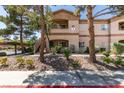 Condominium exterior with a desert landscape, lush trees, and assigned unit numbers at 5751 E Hacienda Ave # 105, Las Vegas, NV 89122