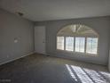 Sun-drenched living room featuring neutral walls, plush carpeting, and arched windows with plantation shutters at 734 Rusty Spur Dr, Henderson, NV 89014