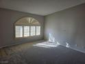 Bright living room featuring neutral walls, plush carpeting, and arched windows with plantation shutters at 734 Rusty Spur Dr, Henderson, NV 89014