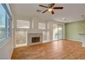 Open living space with wood floors, a ceiling fan, stone fireplace, and backyard access at 7709 Sierra Paseo Ln, Las Vegas, NV 89128