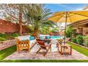 Backyard features a cozy patio with outdoor seating, lush landscaping, and a relaxing ambiance under the sun umbrella at 905 Possum Hill St, Henderson, NV 89014