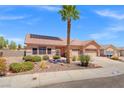 View of home with two car garage, desert landscaping including a palm tree, and a terracotta tile roof with solar panels at 9624 Twelve Pins Dr, Las Vegas, NV 89129