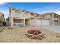 Inviting two-story residence featuring a balcony, a two-car garage, a manicured lawn, and a flower garden at 9815 Ramhorn Canyon St, Las Vegas, NV 89183
