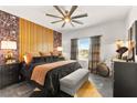 Comfortable primary bedroom featuring unique accent wall, modern ceiling fan, and an abundance of natural light at 12648 Heritage Bend Dr, Las Vegas, NV 89138