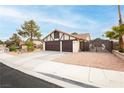 View of a two-car garage and fenced in front yard with desert landscaping at 1528 Tonada Way, Las Vegas, NV 89117