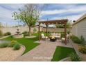 Relaxing backyard with a pergola, seating around a fire pit, water fountain, and lush green lawn at 419 National St, Henderson, NV 89015