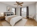 Cozy bedroom featuring neutral walls, wood-look floors, a ceiling fan, and two windows with drapes at 419 National St, Henderson, NV 89015
