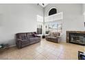 Comfortable living room with large windows, tile floors, and a cozy fireplace at 5950 Pacific Shores Dr, Las Vegas, NV 89142