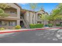 Exterior tan condo building with stairs and balconies, surrounded by greenery and partial blue sky at 8250 N Grand Canyon Dr # 1123, Las Vegas, NV 89166