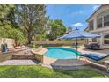 Inviting backyard oasis featuring a sparkling pool, mature trees, and ample seating areas for relaxing at 8320 Opal Cove Dr, Las Vegas, NV 89128