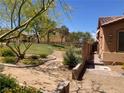 Home's exterior is beside a sidewalk and grassy community area with trees and desert landscaping at 1139 Via Partito, Henderson, NV 89052