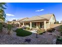 Backyard showcasing a covered patio, rock landscaping, and synthetic grass at 8797 Pinley Spring St, Las Vegas, NV 89113
