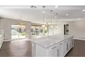 Open-concept kitchen featuring a large island, hardwood floors, pendant lighting, and sliding glass doors to backyard at 8797 Pinley Spring St, Las Vegas, NV 89113