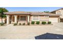 Inviting single-story home with a tile roof and attached two-car garage, surrounded by green bushes at 1440 Summer Glow Ave, Henderson, NV 89012