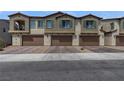 Exterior view of townhomes featuring stucco exteriors, brick driveways, and attached garages at 236 Callen Falls Ave # 1211, Henderson, NV 89011