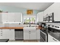 Modern kitchen featuring white cabinets, butcher block countertops, stainless steel appliances, and a farmhouse sink at 2426 La Pluma St, Henderson, NV 89014