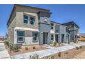 Modern two-story townhome with a neutral exterior, walkway, and small decorative shrubs at 6104 Aster Garden St # 129, North Las Vegas, NV 89081