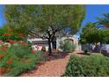 Lovely two-story home featuring mature trees and colorful flowering bushes in the front yard at 614 Ravenglen Dr, Las Vegas, NV 89123