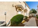 Front exterior with a well manicured lawn, pathway to a white front door and beige facade at 6576 Buster Brown Ave # 101, Las Vegas, NV 89122