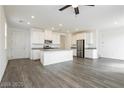 A spacious open concept kitchen and living area features gray wood floors, modern lighting, and white cabinets at 7777 Vino Vranec Ct, Las Vegas, NV 89113