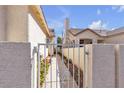 A peek through the iron gate offers a glimpse of the landscaped backyard and walkway at 9562 Collinsleap Ct, Las Vegas, NV 89123