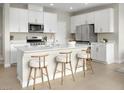 Modern kitchen features white cabinets, stainless steel appliances, a center island with seating, and modern countertops at 10029 Luna River Ave, Las Vegas, NV 89148