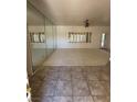 Bright living room featuring neutral walls, tile flooring, a mirrored wall, and large windows at 2562 Downeyville Ave, Henderson, NV 89052
